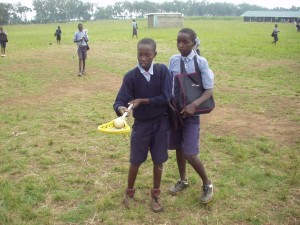 Two Kenyan students looking at a lacrosse stick donated by World teacher aid